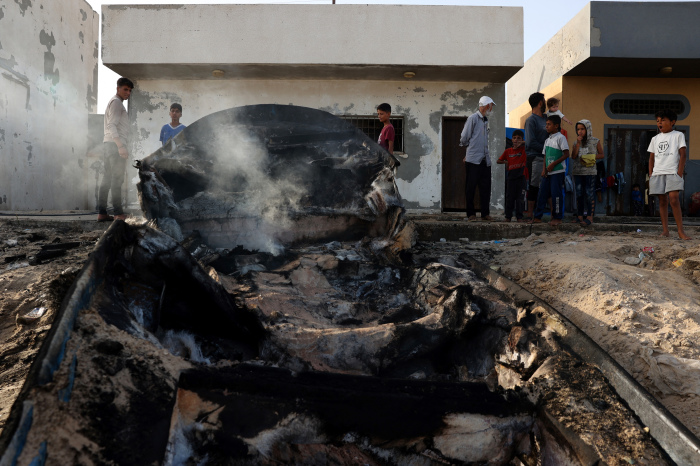 Palestinians stand around a charred fishing boat that was hit by an Israeli airsrike on the Mediterranean coast of Rafah in the southern Gaza Strip on May 22, 2024, amid the ongoing conflict between Israel and the Palestinian Hamas group.